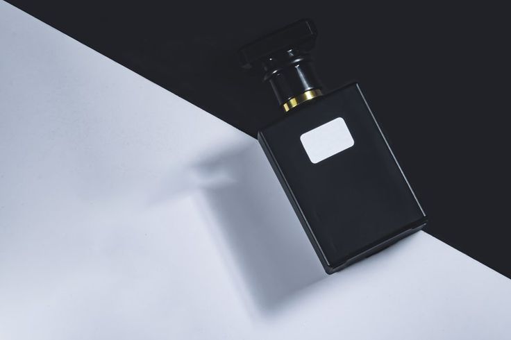 Black and gold perfume bottle isolated on a black and white diagonal background_ Blank product mockup template design for ads